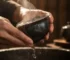 Hands rinsing a Jian Zhan tea cup under warm running water, showing the proper daily cleaning method for Tenmoku tea bowls