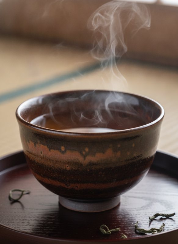 Tenmoku tea cup with oolong tea on wooden tray