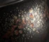 Close-up of a Jian Zhan tea cup showing reddish-brown iron oxidation marks on oil spot glaze crystals