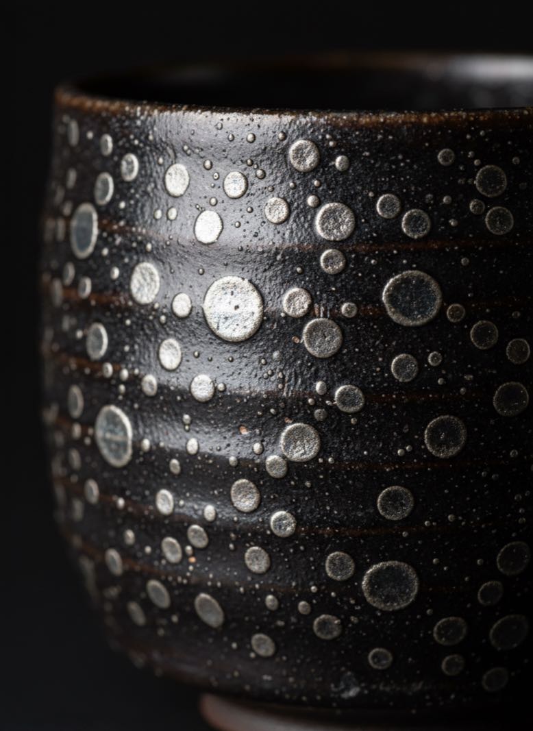Tenmoku Glaze Pattern 1 Tenmoku oil spot glaze pattern showing round metallic silver crystals on dark surface