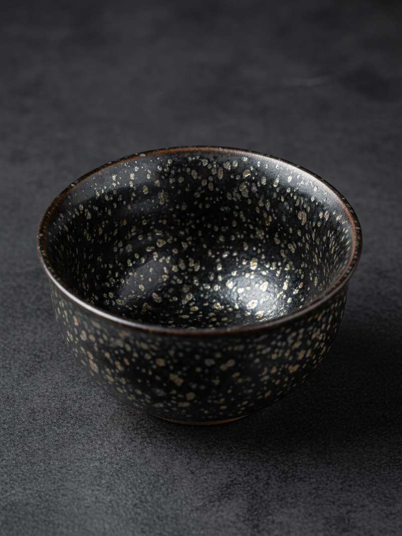 Tenmoku tea cup with oil spot glaze pattern showing metallic crystalline spots Tenmoku tea cup with oil spot glaze pattern showing metallic crystalline spots