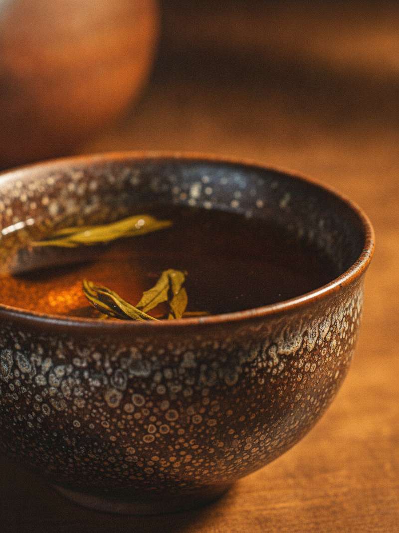 Close-up of tenmoku oil-spot glaze with green tea leaves